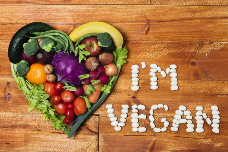 Kas ir vegāns – sirds forma no augļiem un dārzeņiem ar uzrakstu “I’m vegan” pupiņās uz koka virsmas