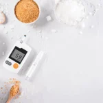 Glikozes mērītājs ar dažādu veidu cukuru uz balta fona.